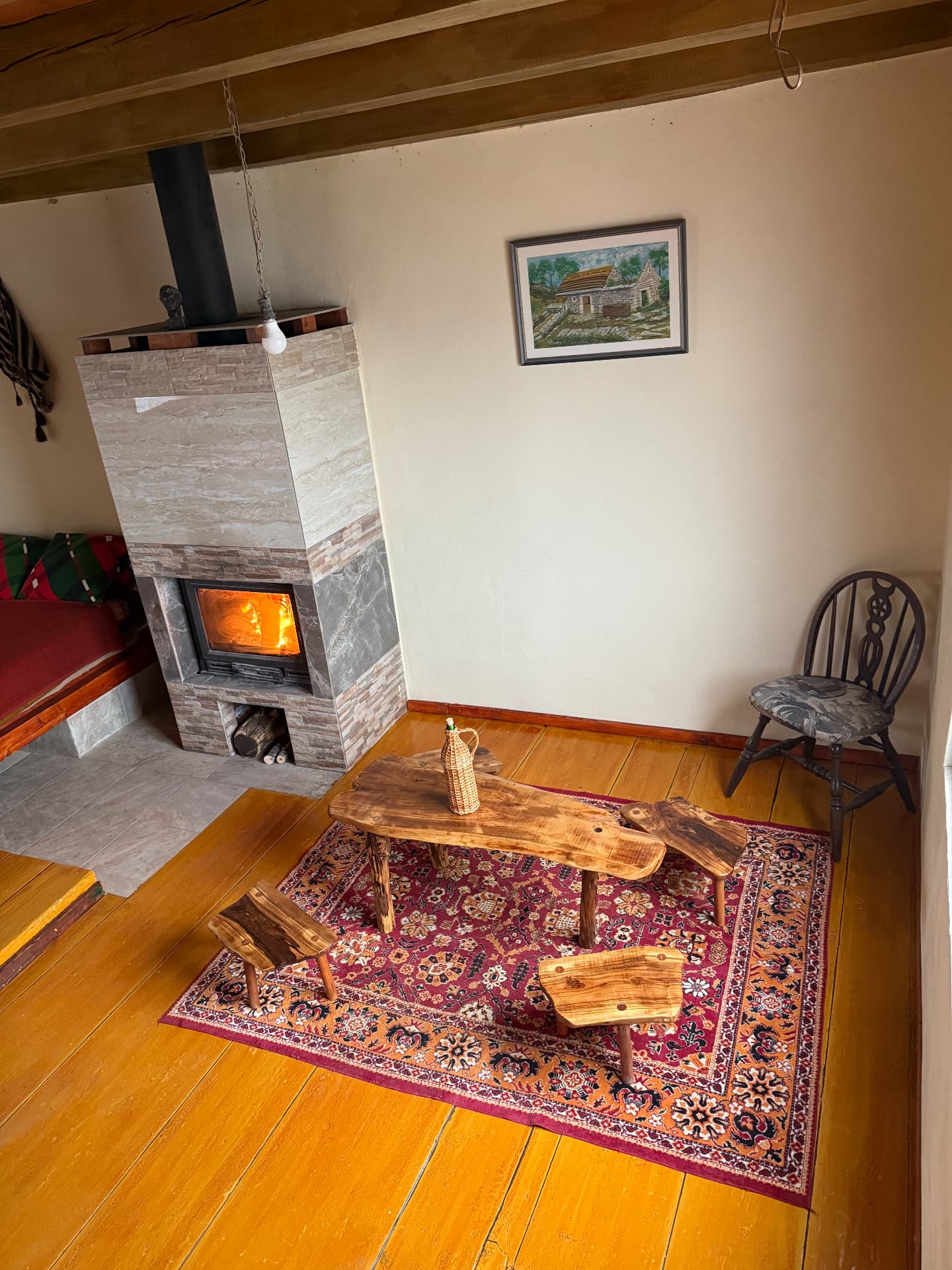 Small lounge corner with handmade wooden table and carpet by the stove