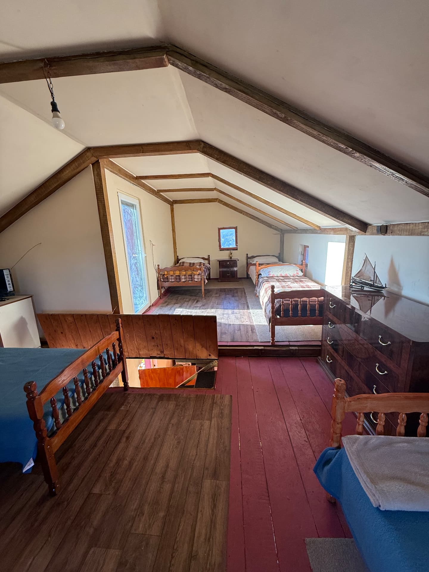 Attic sleeping space under the beams with simple wooden beds