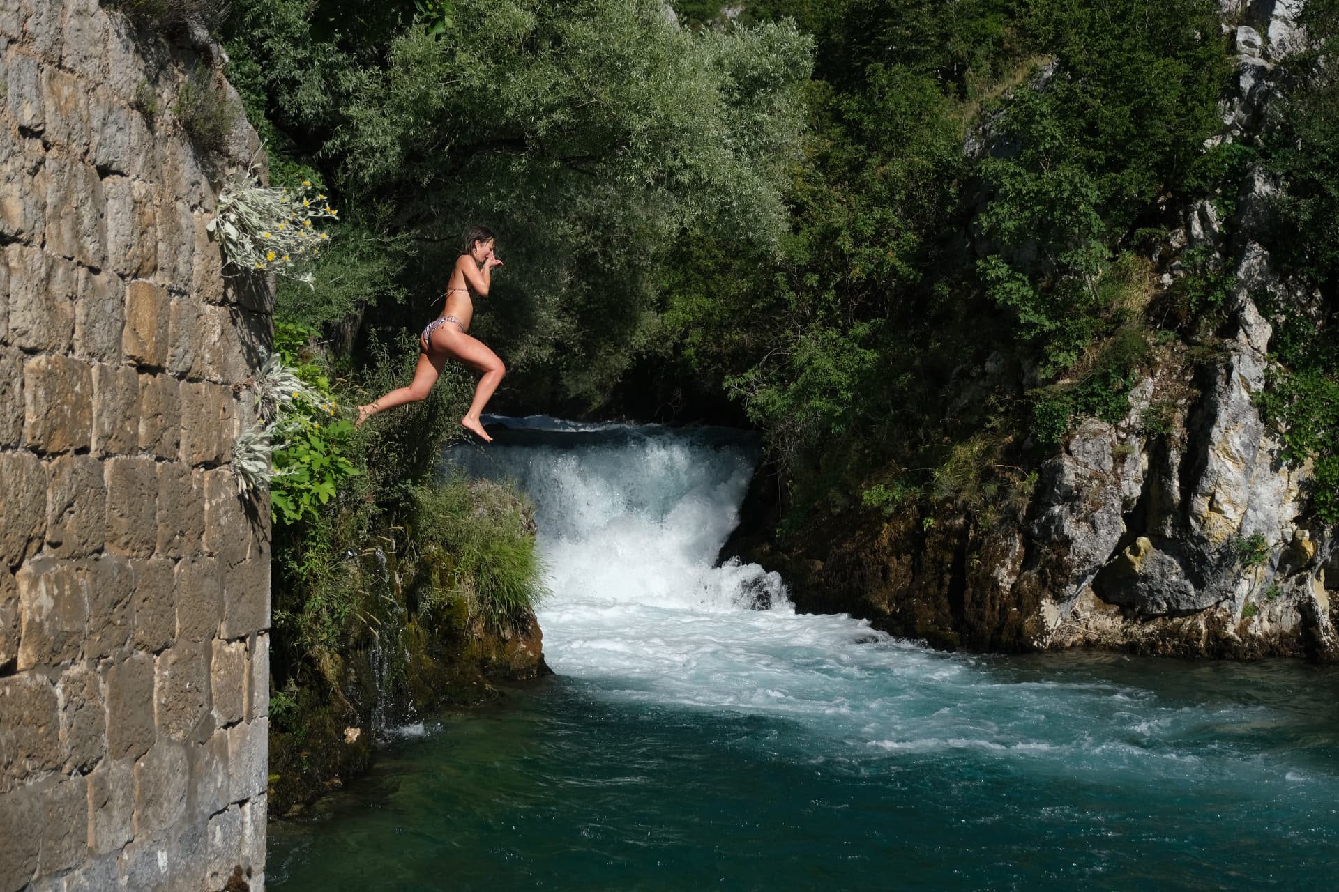 A guest jumping from the stone wall into the turquoise river on river day