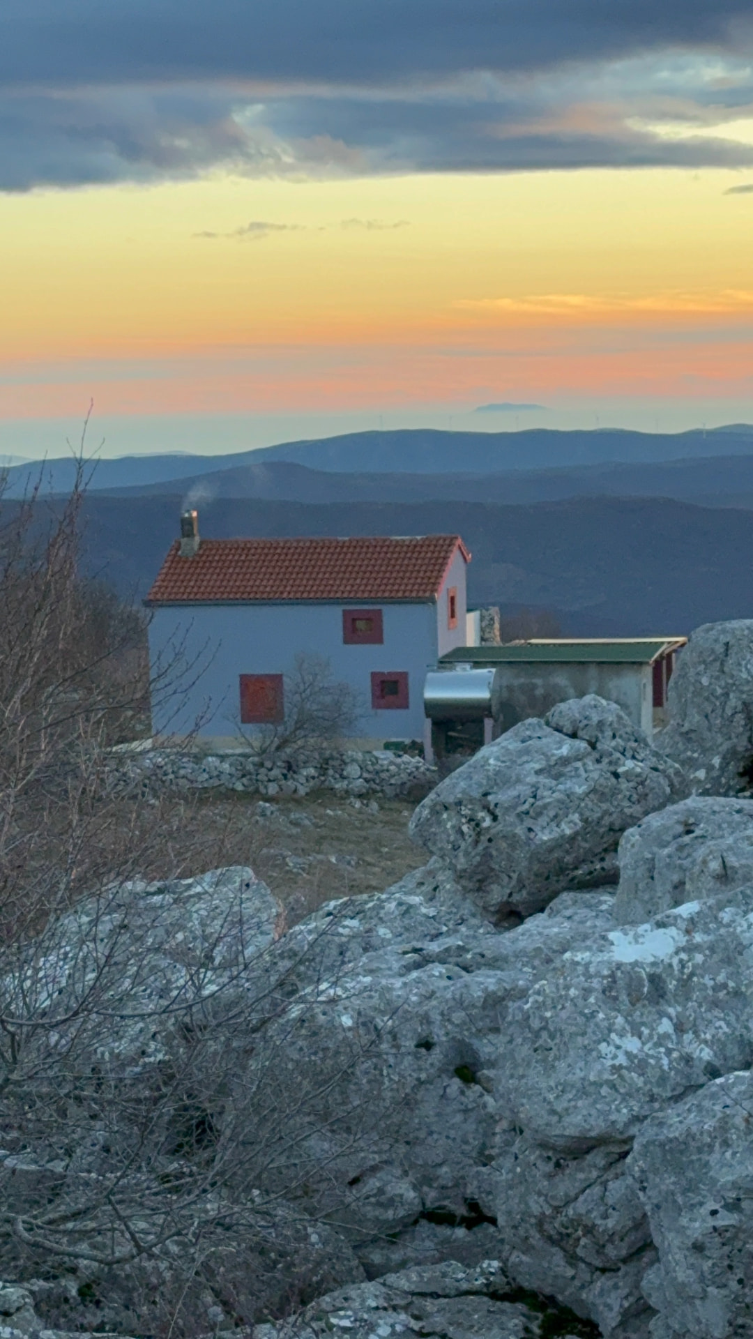 The mountain house at dusk, warm light in the windows