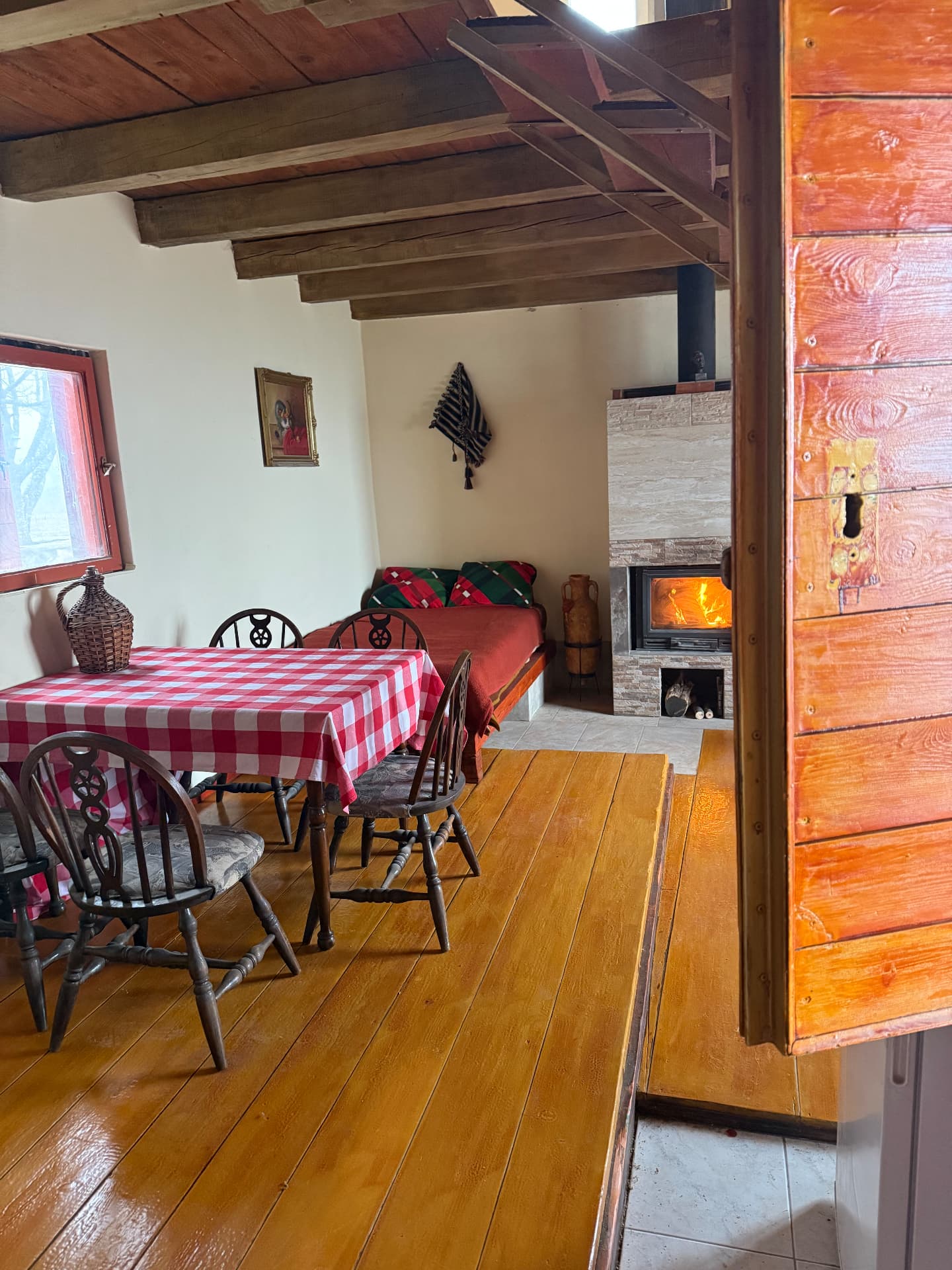 Dining room with wooden beams, old floorboards and the fire going