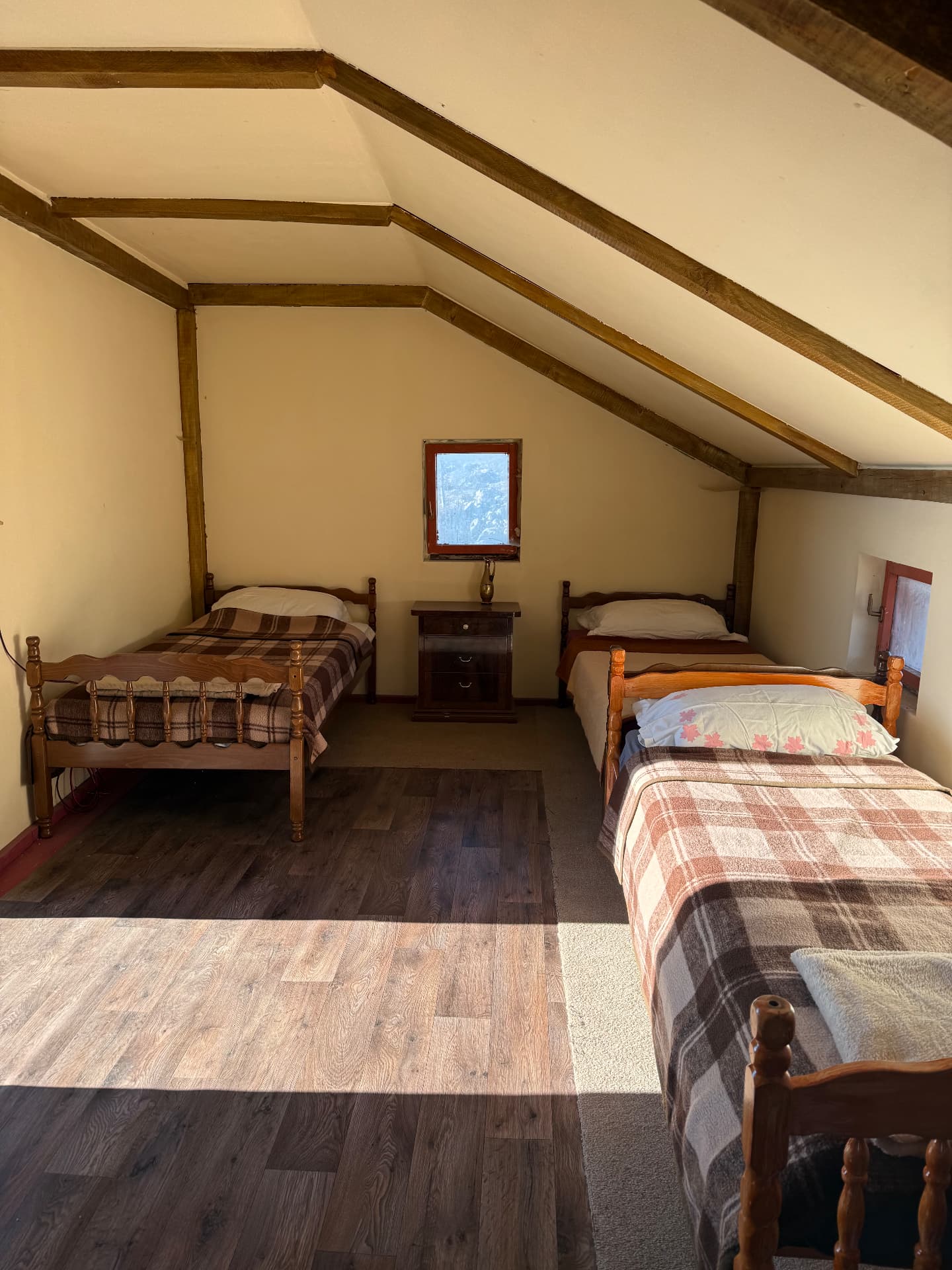 Beds under the sloped attic roof with a small window to the mountain