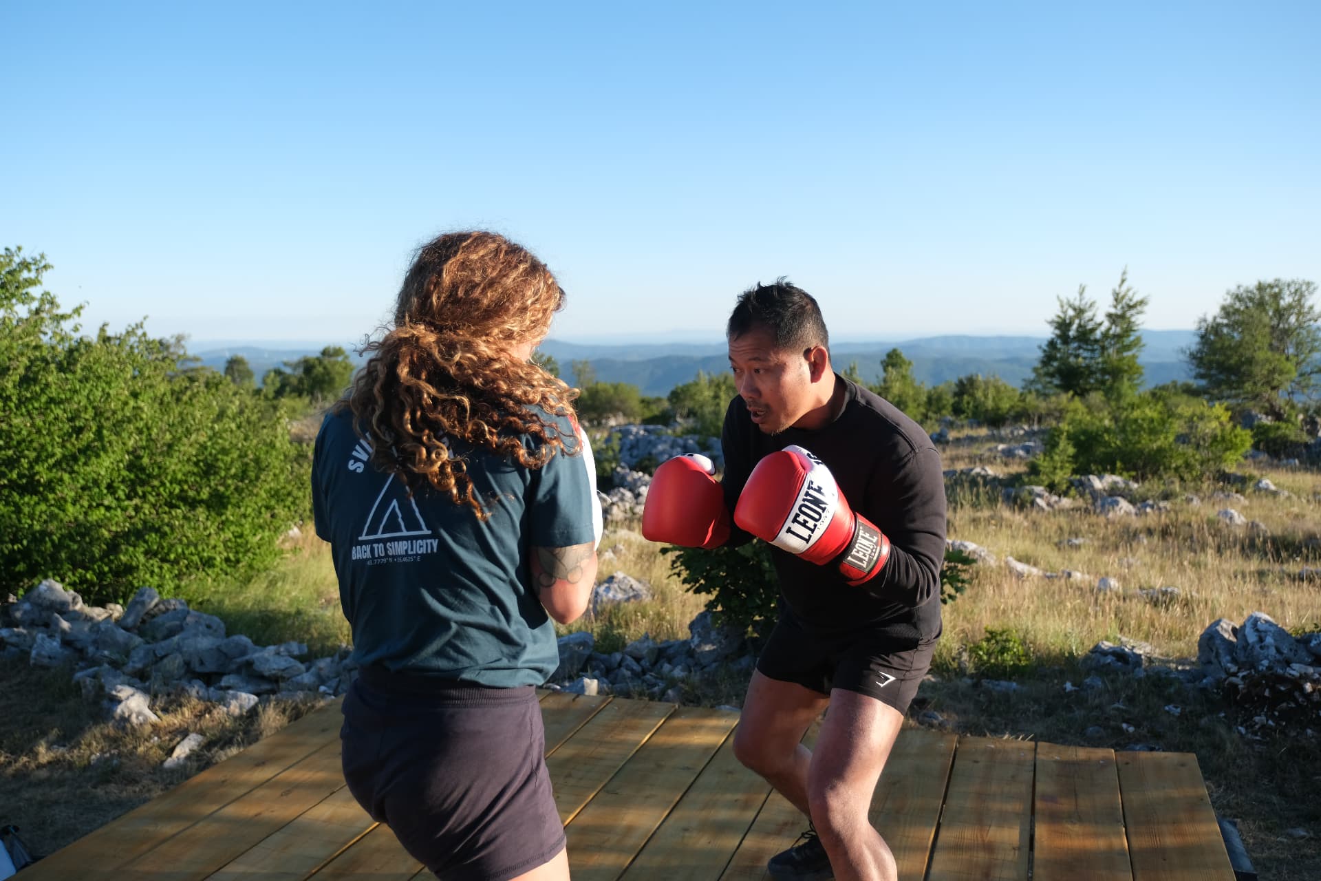 Close-up of pad work on the deck, the late sun catching the BACK TO SIMPLICITY shirt